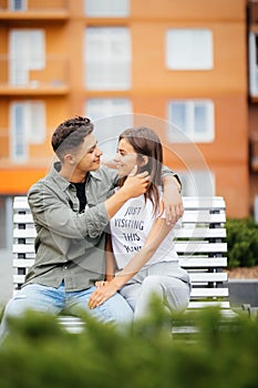 Happy young couple teenagers are sitting on the bench city in the summer sunny day