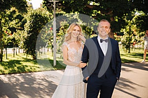 Happy young couple in their wedding day spend time in park. Green background