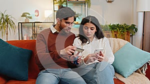 Happy young couple together doing online shopping by entering credit card number on smartphone