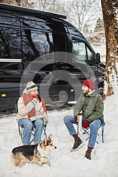 Happy young couple travelling by van in winter forest