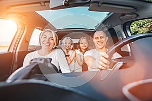 Happy young couple with two daughters inside car during auto trop. They are smiling, laughing during road trip. Family values, photo