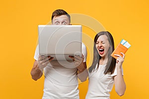 Happy young couple two friends in white t-shirts posing isolated on yellow orange background. People lifestyle concept