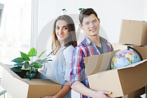 Happy young couple unpacking or packing boxes and moving into a