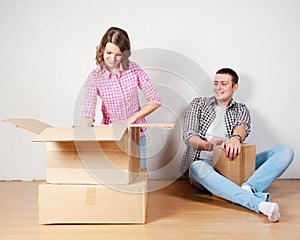 Happy young couple unpacking or packing boxes and moving into a new home.