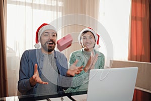 happy young couple use or watch something on laptop pc for christmas