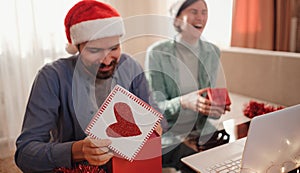 happy young couple use or watch something on laptop pc for christmas