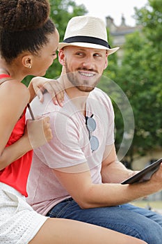 Happy young couple using digital tablet outdoors