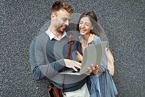 Happy young couple using laptop outdoor. Travel, business, people fun concept