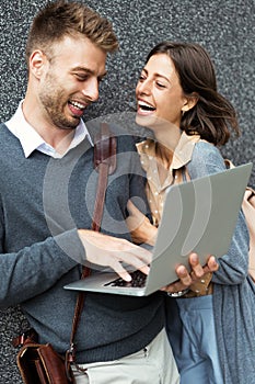 Happy young couple using laptop outdoor. Travel, business, people fun concept
