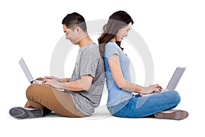 Happy young couple using laptop while sitting back to back