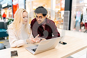 Happy young couple using typing laptop computer together, discussing purchase on the Internet, looking to screen sitting