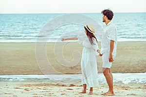 Happy young couple walk on the beach on honeymoon.