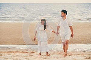 Happy young couple walk on the beach on honeymoon.