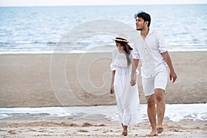 Happy young couple walk on the beach on honeymoon.