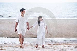 Happy young couple walk on the beach on honeymoon.