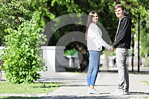 Happy young couple walking in green park on sunny spring day