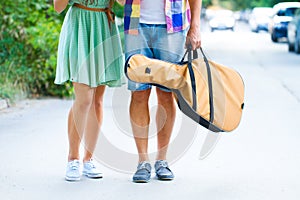 Happy young couple walking with guitar drinking juice spending c