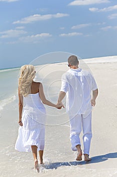 Happy Young Couple Walking Holding Hands on Beach