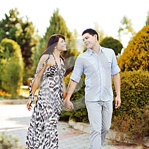 Happy young couple walking together in a green park