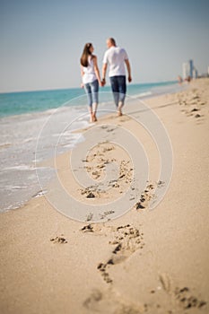 Happy young couple walking on a tropical beach. Lovers in full body length on beach. Back rear view.
