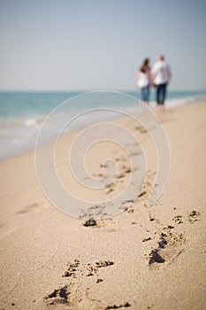 Happy young couple walking on a tropical beach. Lovers in full body length on beach. Back rear view. Honeymoon couple