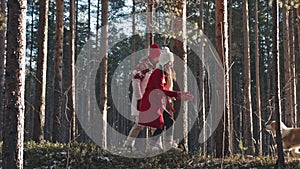 Happy young couple walking in winter forest with their doggy. Xmas holidays concept. Family weekend spend time together