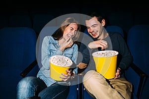 Happy young couple watching comedy movie in cinema, smiling