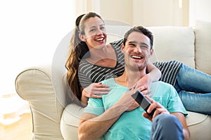 Happy young couple watching television together on sofa