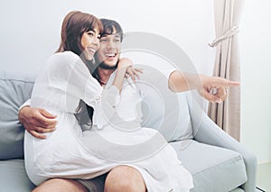 Happy young couple watching TV in living room.