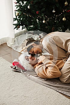 Happy young couple wearing Christmas decor having fun at home near Christmas tree