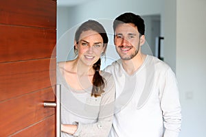 Happy young couple welcoming guests into their home