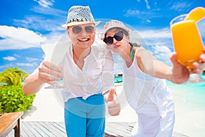 Happy young couple in white clothes having fun with delicious cocktails by the beach