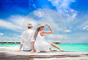 Happy young couple in white clothes relaxing by the beach