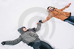Happy Young Couple in Winter . Family Outdoors. man and woman looking upwards and laughing. Love, fun, season and people