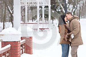 Happy young couple in winter park love and kiss