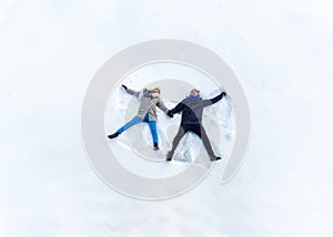 Happy Young Couple in Winter Park Lying On Snow. Making Snow Angel. top view