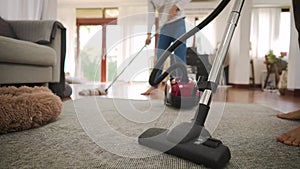Happy young couple of woman cleaning carpet with vacuum cleaner machine and man mopping the floor at modern home