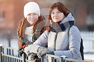 Happy young couple women in winter season, two girlfriends portrait in sunlight on urban street