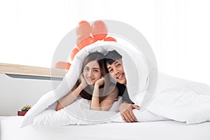 A happy young couples are in bed under the blanket.