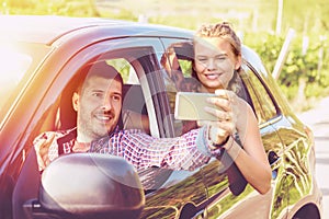 Happy young couples on road trip taking selfie while driving on countryside road