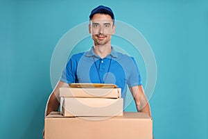 Happy young courier with parcels and envelopes on background