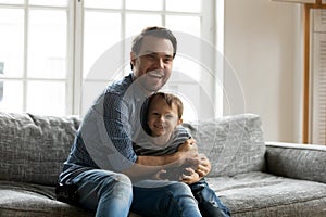 Happy young dad play relax with small son at home