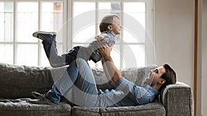 Happy young daddy playing airplane with boy son.