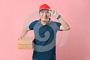 Happy young delivery man in red cap standing with parcel post box