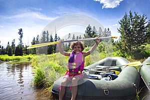 Happy Young diverse boy paddling in an inflatable raft on the river while on a family vacation