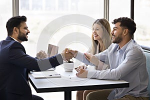 Happy young diverse couple shaking hands with Indian consultant