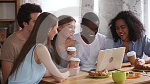 Happy young diverse friends having fun watching comedy on laptop