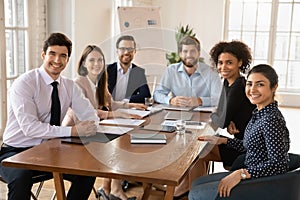 Happy young diverse team of professionals posing at office table