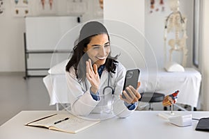 Happy young doctor woman talking on video call to patient