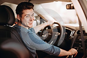 Happy young driver behind the wheel of a car. Buying a car and driving concept.